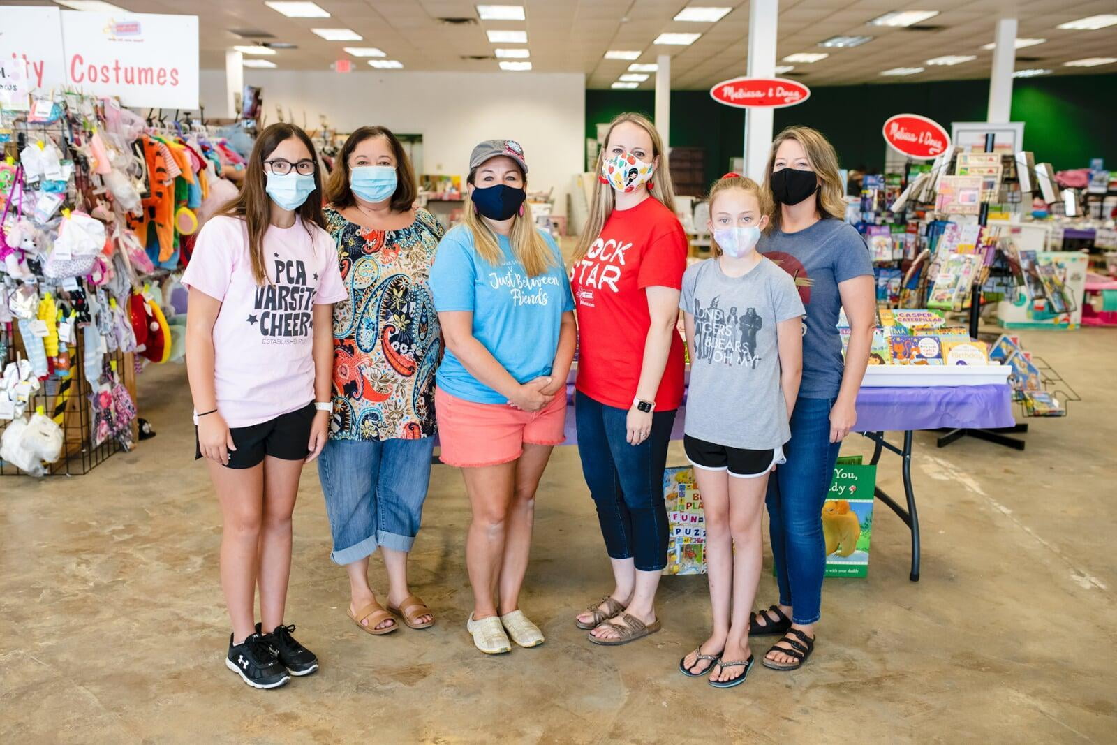 A group of shoppers wearing masks for safety reasons gathers together at the sale to shop.